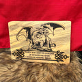 Wooden plaque with dragon design and quote on a red fabric background