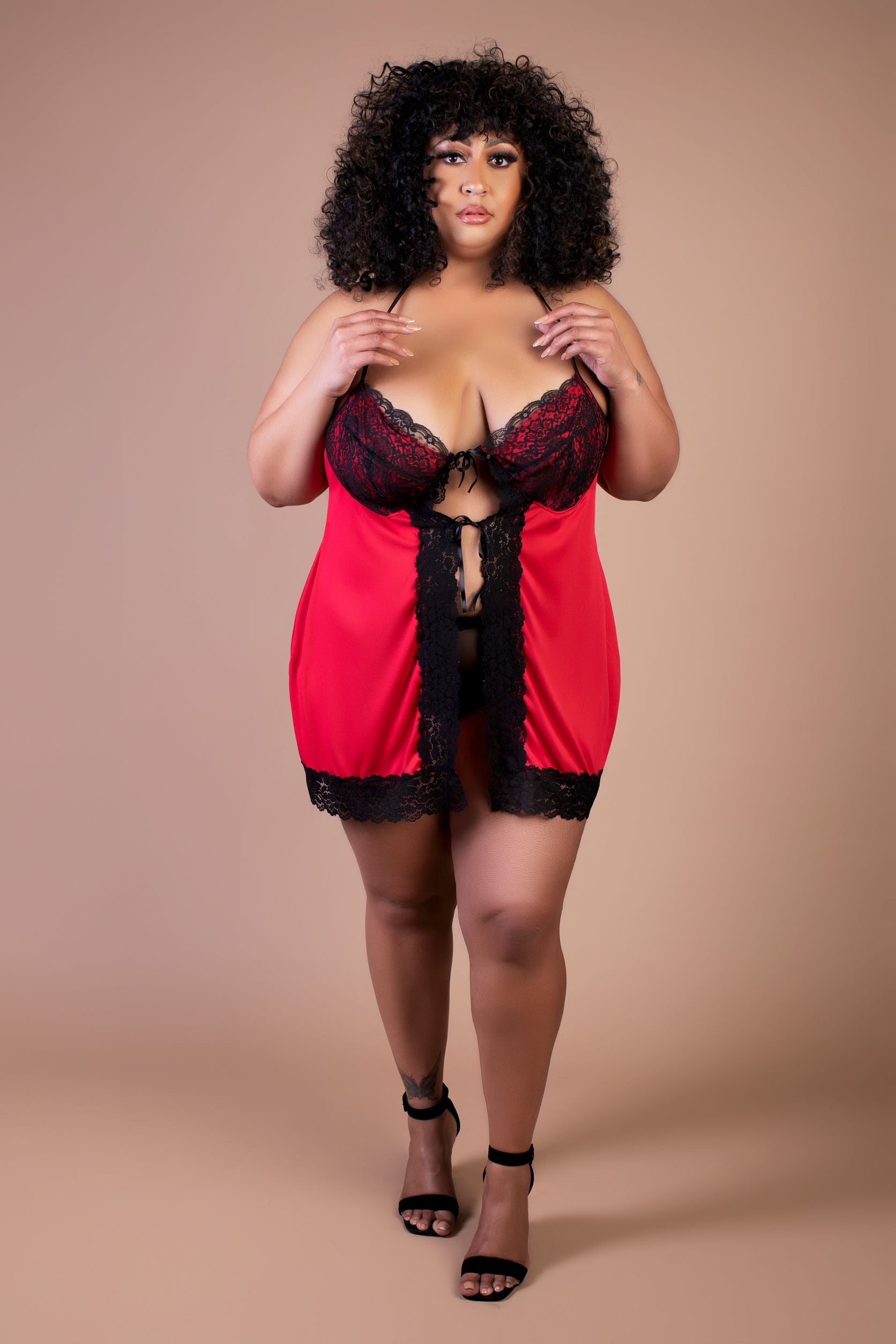 Woman wearing a red and black lace lingerie set against a beige background